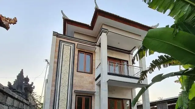 Two-storey house with a carved stone facade panel and a Balinese roof profile