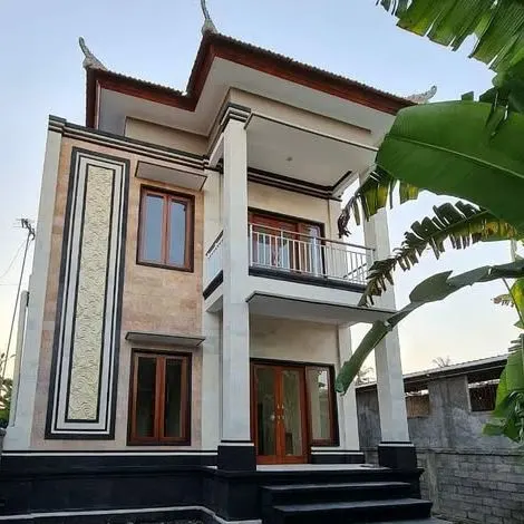 Two-storey house with a carved stone facade panel and a Balinese roof profile